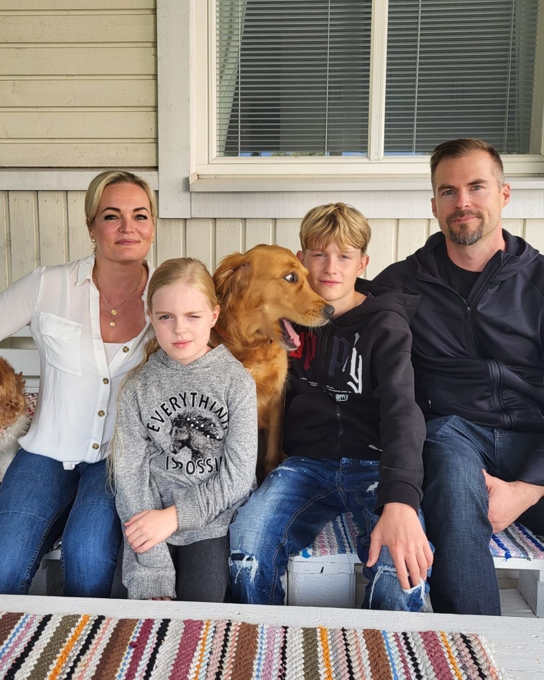 Mannermaan perhe poseeraa terassilla koiriensa kanssa. 